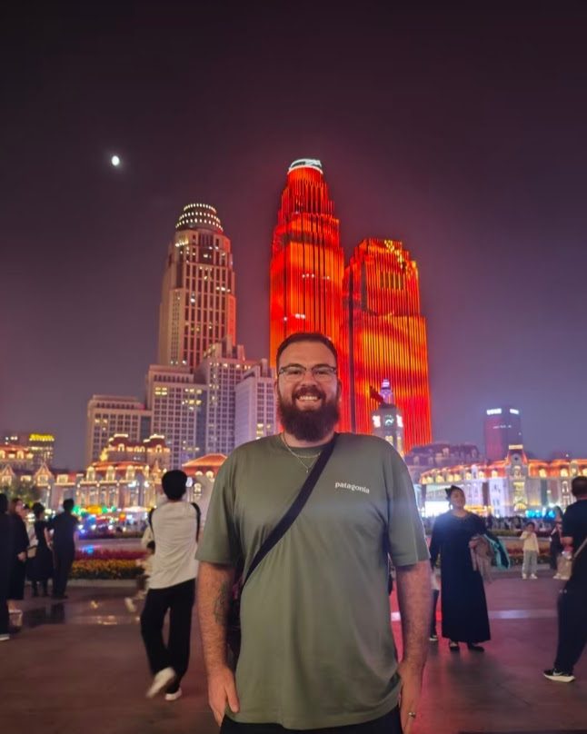 Teacher Reed in front of the Tianjin skyline lit up at night