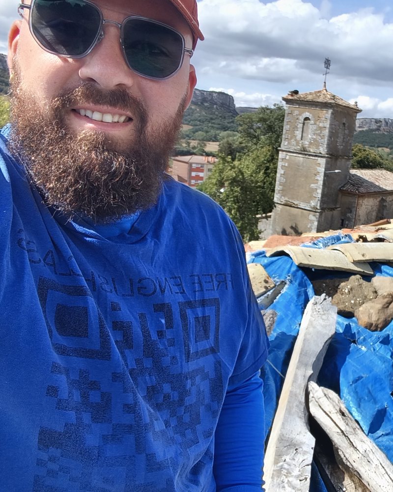 Teacher Reed on a rooftop in a village in northern Spain, church tower behind